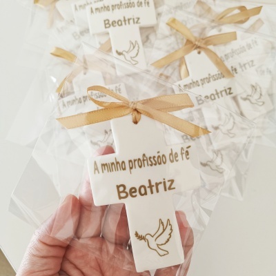 Cruz branca de cerâmica com texto e pomba dourada embalada com fita bege