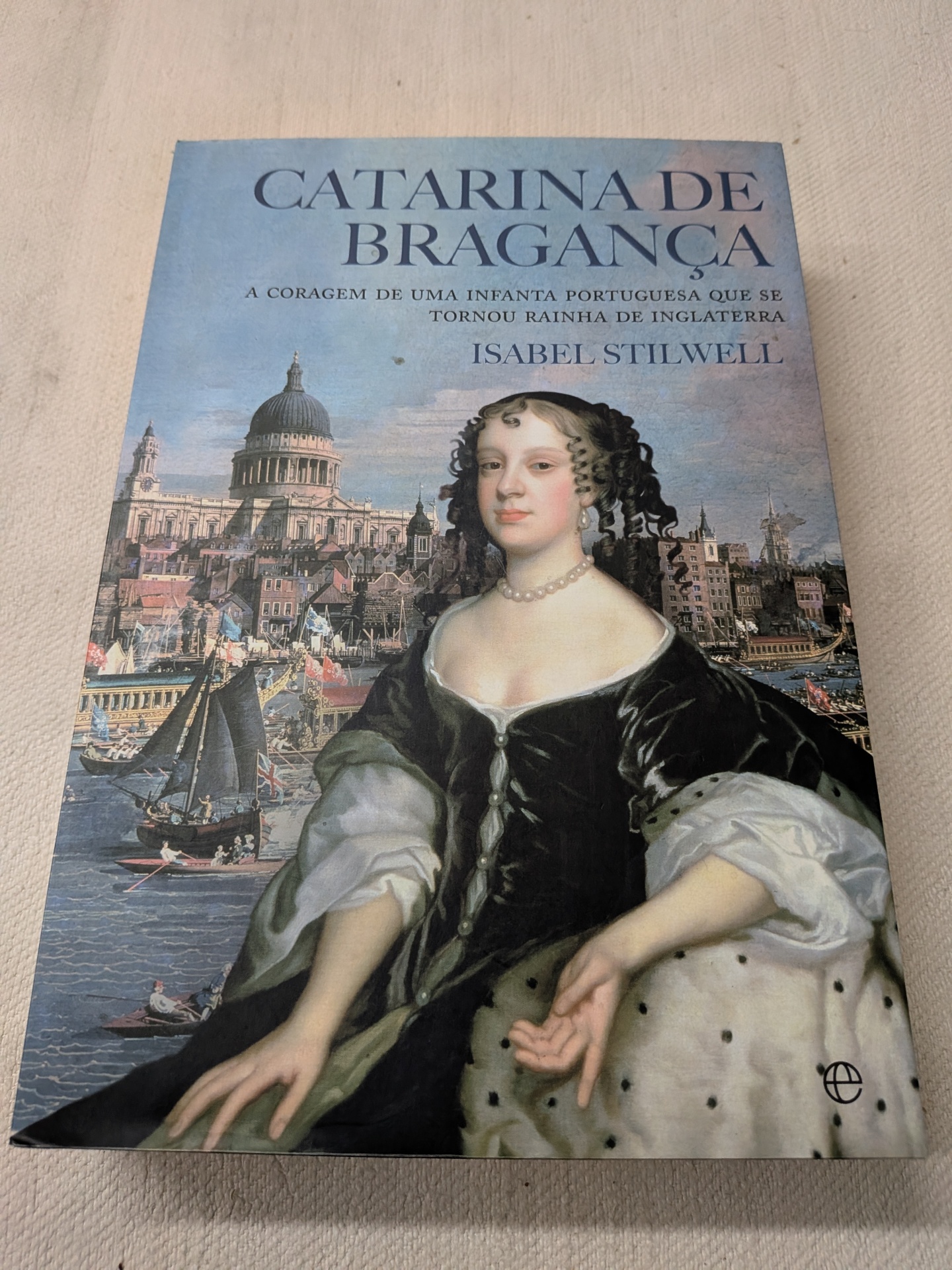 Isabel Stilwell - Catarina de Bragança - Princesa de Portugal e Rainha de Inglaterra Capa do livro Catarina de Bragança com retrato feminino e paisagem urbana ao fundo