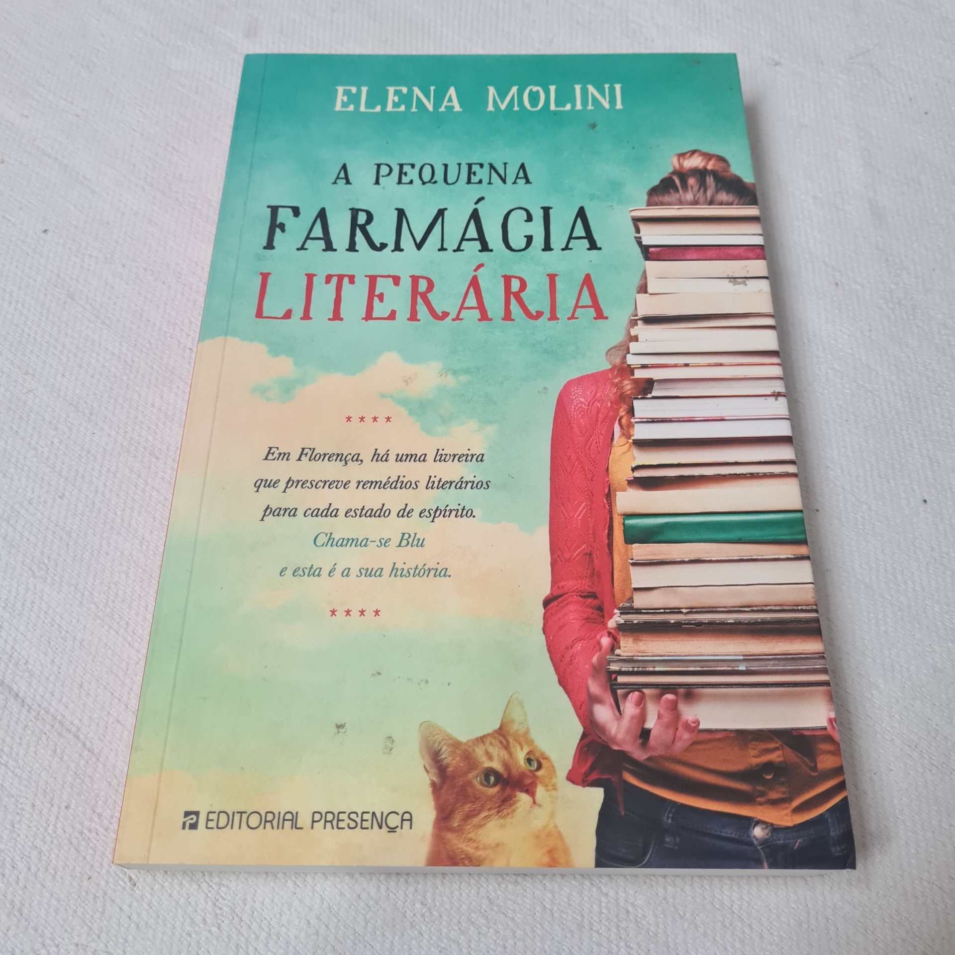 Elena Molini - A Pequena Farmácia Literária Capa do livro 'A Pequena Farmácia Literária' com pessoa e gato