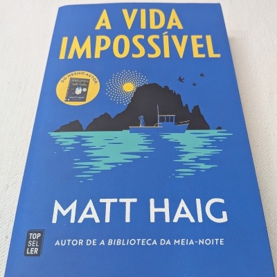 Livro A VIDA IMPOSSÍVEL de Matt Haig com capa azul e ilustração de barco e montanha.