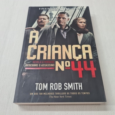 Capa do livro 'A Criança Nº 44' com três personagens e texto em bege, vermelho e branco