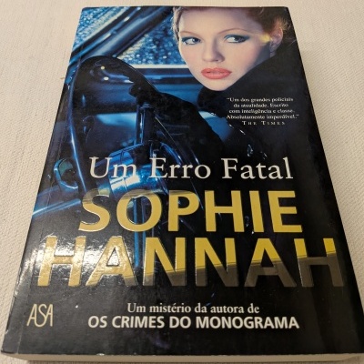 Capa do livro Um Erro Fatal de Sophie Hannah com imagem de mulher no carro e texto em destaque.