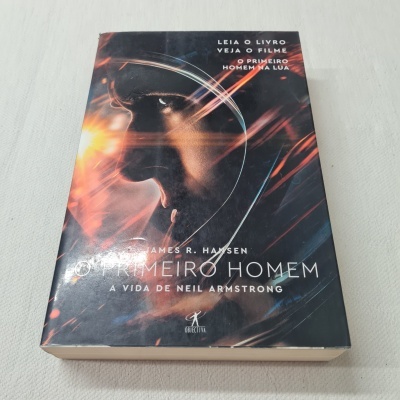 Capa de livro com rosto de astronauta e texto relacionado a Neil Armstrong.