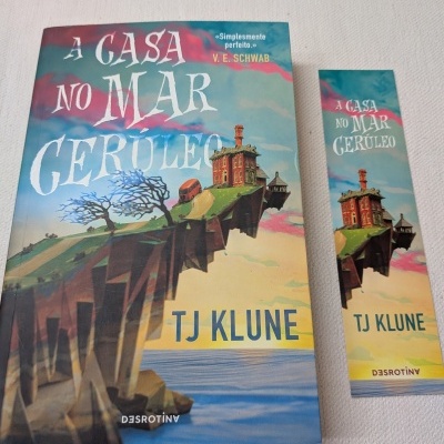 Livro 'A Casa no Mar Cerúleo' de TJ Klune com marcador de livros correspondente.