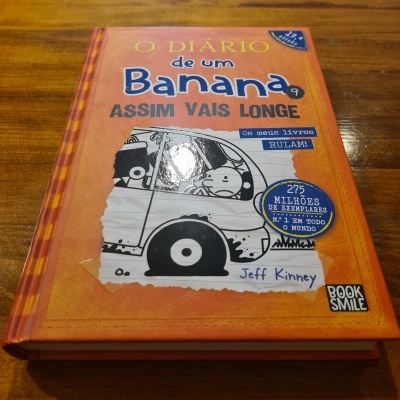 Livro capa dura laranja com título e ilustração a preto e branco de carrinha