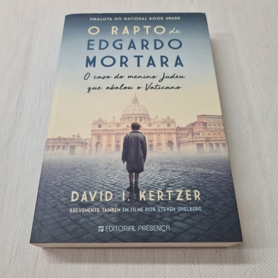 Capa do livro O Rapto de Edgardo Mortara com rapaz de costas e edifícios ao fundo