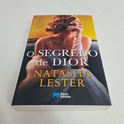 Livro 'O SEGREDO de DIOR' com capa ilustrada por mulher vestida com vestido e luvas brancas