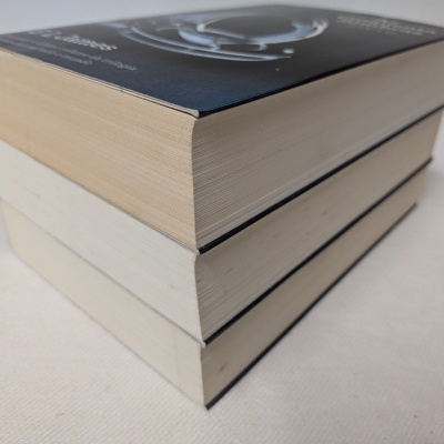 Três livros empilhados de capa dura sobre superfície clara