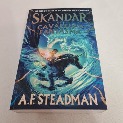 Livro Skandar Cavaleiro Fantasma com capa azul e cavaleiro montado num cavalo fantasma