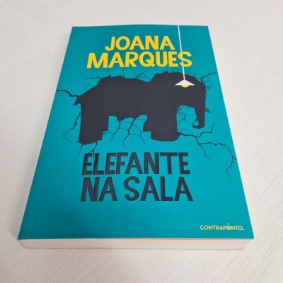 Livro 'Elefante na sala' de Joana Marques com capa azul e elefante preto na parede.