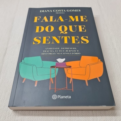 Capa de livro azul escura com título FALA-ME DO QUE SENTES e ilustração de duas cadeiras coloridas e mesa com lenços.