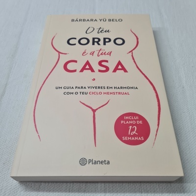 Capa de livro 'O teu corpo é a tua casa' com desenho de corpo feminino e texto em cores creme, preto e vermelho
