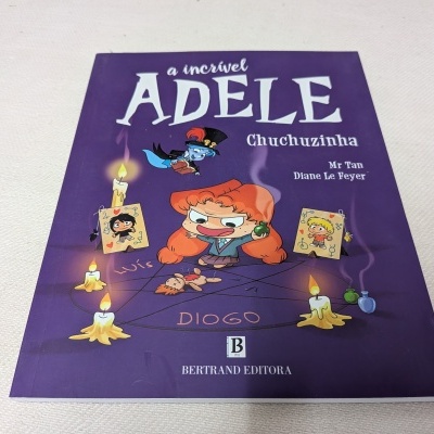 Capa de livro infantil roxa com personagem ruiva ao centro e velas acesas