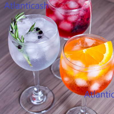 Três taças de vidro com bebidas coloridas e gelo sobre mesa de madeira.