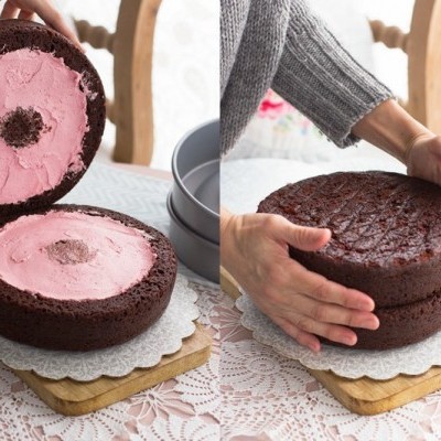Bolo de chocolate com recheio rosa montado sobre base rendada em mesa com toalha branca
