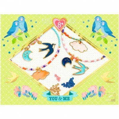 Conjunto de colares infantis coloridos com pendentes de lua, nuvem e andorinha sobre fundo verde decorado