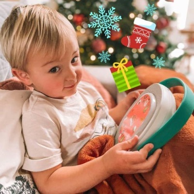 Criança loira com tablet verde e fundo de Natal decorado