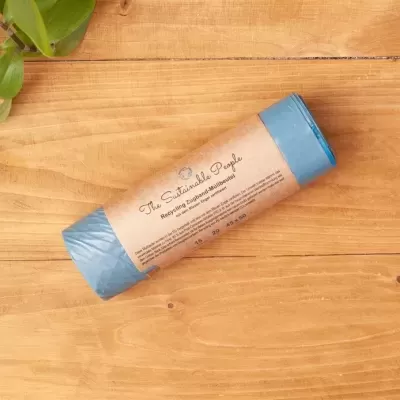 Rolo azul de saco de lixo com rótulo de papel castanho sobre madeira