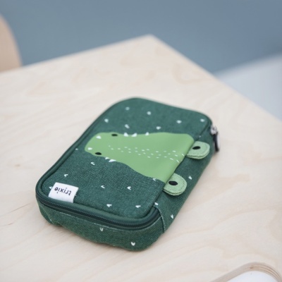 Estojo escolar verde com desenho de crocodilo em tecido sobre mesa de madeira clara