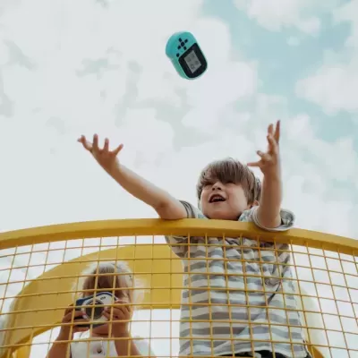 Crianças em estrutura amarela a brincar com consola portátil azul