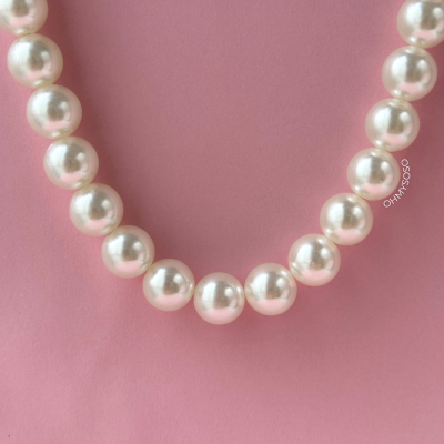 Colar de pérolas brancas sobre fundo rosa