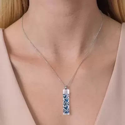 Colar prateado com pendente azul e branco num pescoço feminino