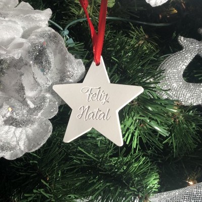 Estrela branca com texto Feliz Natal pendurada numa árvore de Natal