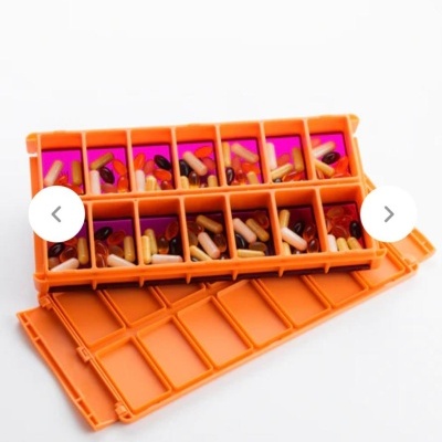 Caixa mensal de comprimidos plástica laranja com cápsulas e comprimidos de várias cores