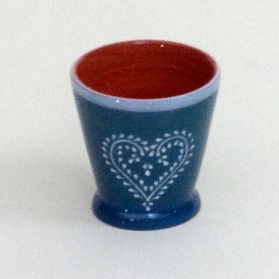 Copo de cerâmica azul com padrão de coração branco e interior vermelho