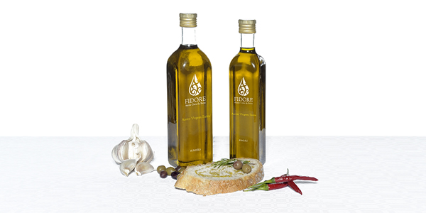 Duas garrafas de azeite, alho, pão e malaguetas sobre fundo branco