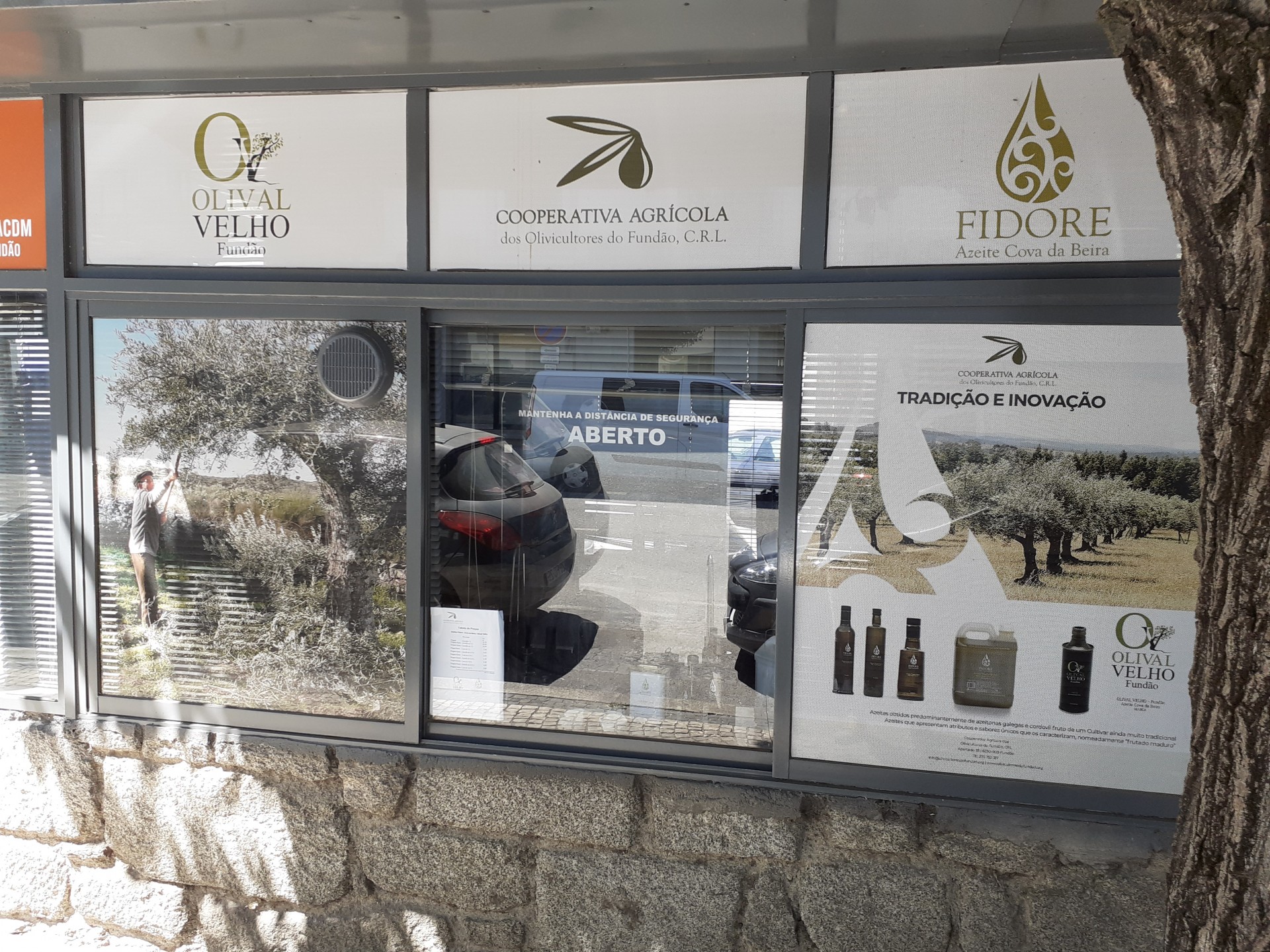 Fachada com publicidade de azeite e marcas, janela com texto ABERTO