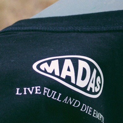 T-shirt preta com estampa branca 'MADAS' e frase 'LIVE FULL AND DIE EMPTY'