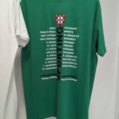 T-shirt verde com brasão e texto impresso nas costas, pendurada num cabide branco