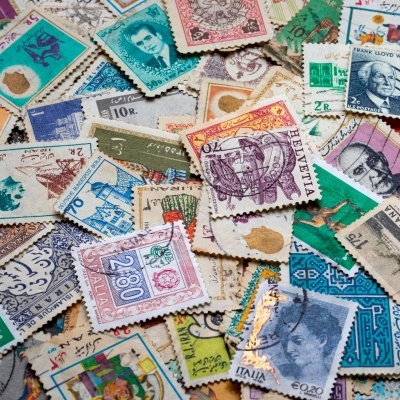 Conjunto diversificado de selos postais coloridos com textos variados sobre superfície texturizada