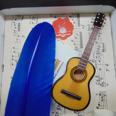 guitarra miniatura, pena azul e pauta musical
