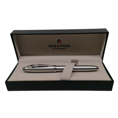 Caneta prateada numa caixa preta com interior bege e texto da marca Sheaffer.