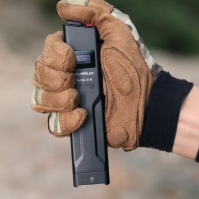 Dispositivo preto de defesa segurado por mão com luva tática