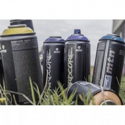 Latas de tinta spray pretas com tampas coloridas em relva