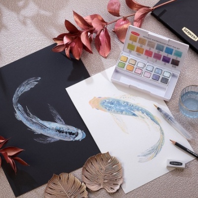 Paleta de aguarela, desenhos de peixes, folhas decorativas e material de arte sobre mesa