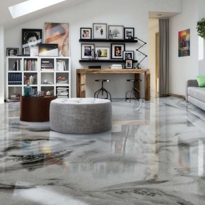 Sala de estar com chão em mármore cinza e branco, mesa de madeira, estante com livros e pufs redondos.