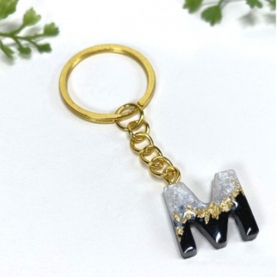 Porta-chaves dourado com pendente letra M preto, branco e dourado