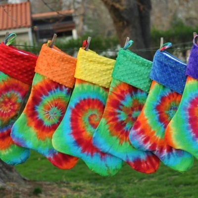 Meias de Natal coloridas com padrão tie-dye penduradas num cordel ao ar livre