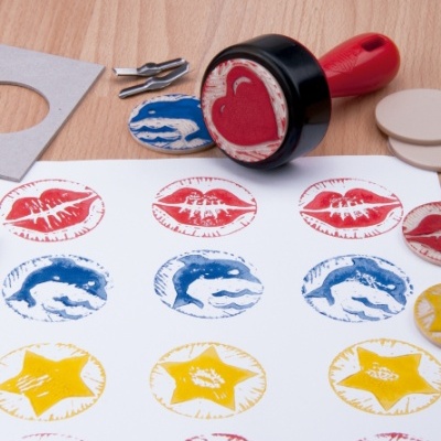 Carimbo vermelho com coração e carimbos coloridos em papel branco sobre mesa