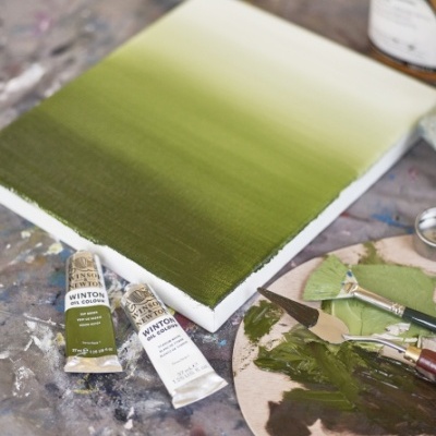 Tela com pintura verde, tubos de tinta Winton, pincel e espátulas sobre paleta de metal.