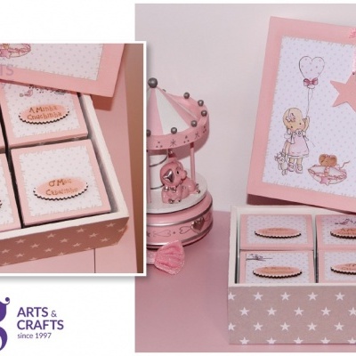 Caixa rosa com quatro sabonetes artesanais etiquetados, em mesa com carrossel decorativo rosa.