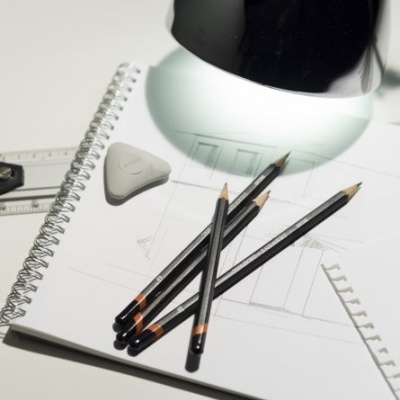 Lápis de desenho, borracha e caderno espiralado com esboços