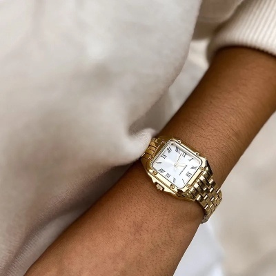 Relógio de pulso dourado com mostrador quadrado branco e números romanos.