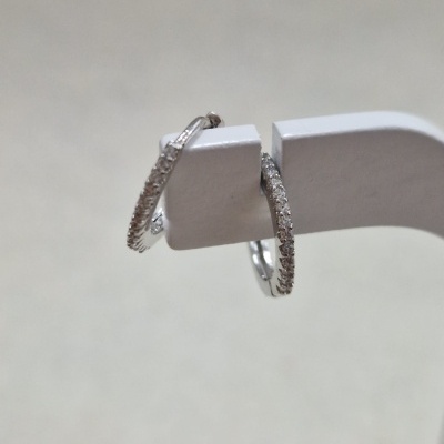 Brincos de argola prateados com textura brilhante pendurados em suporte branco