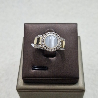 Anel com pedra branca redonda e pedras brilhantes em caixa de apresentação