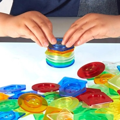 Criança a montar torre com peças coloridas de plástico translúcido